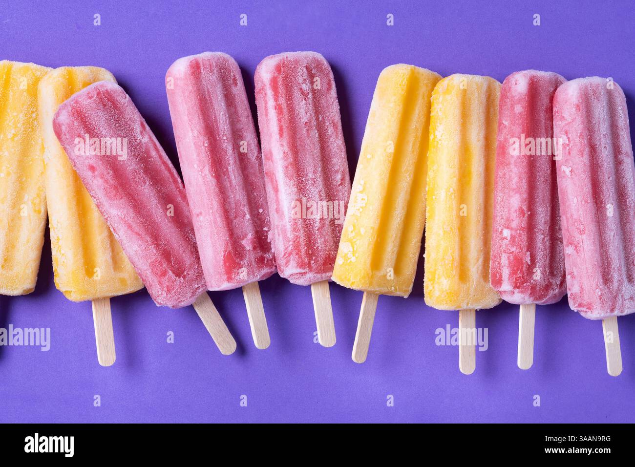 Popsicles orange et rose sur fond violet Banque D'Images