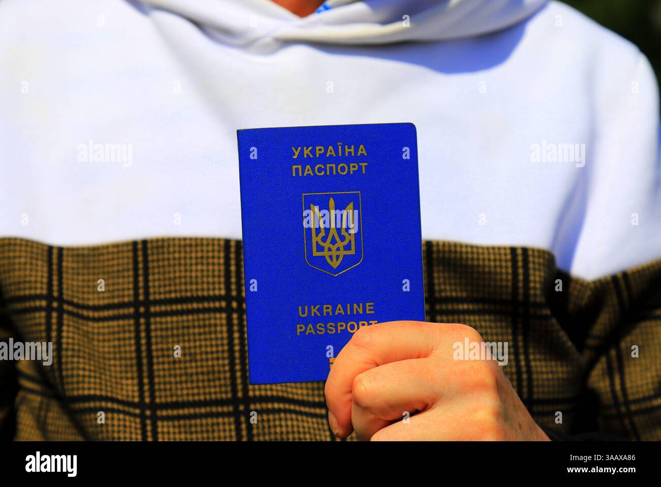 L'homme tient dans les mains passeport avec inscription en ukrainien - passeport de l'Ukraine et emblème d'État de l'Ukraine. Concept voyage, réfugié, touriste, émigré Banque D'Images