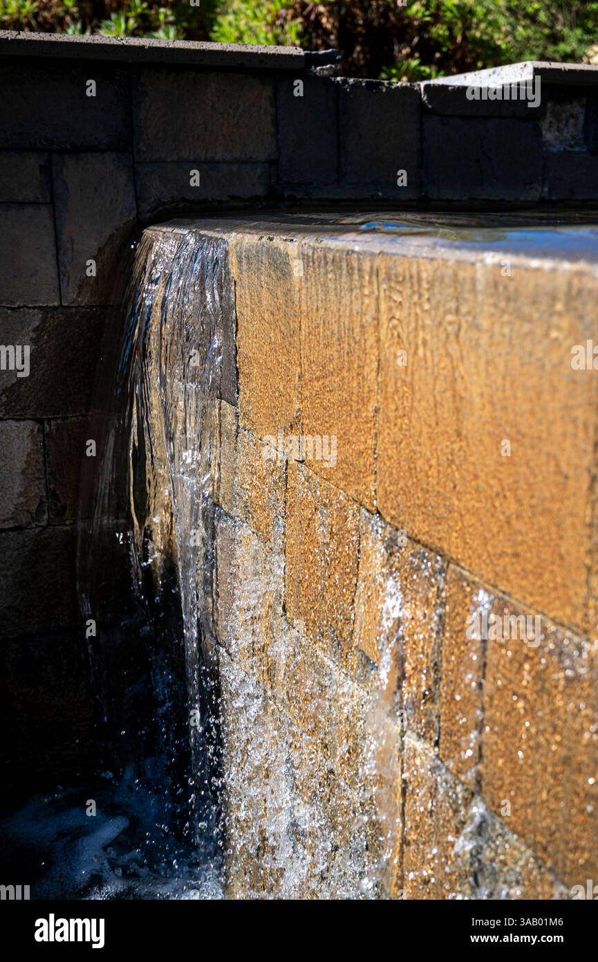 Un mur avec une caractéristique d'eau sur elle. L'eau tombe du haut du mur et éclabousse sur le sol Banque D'Images