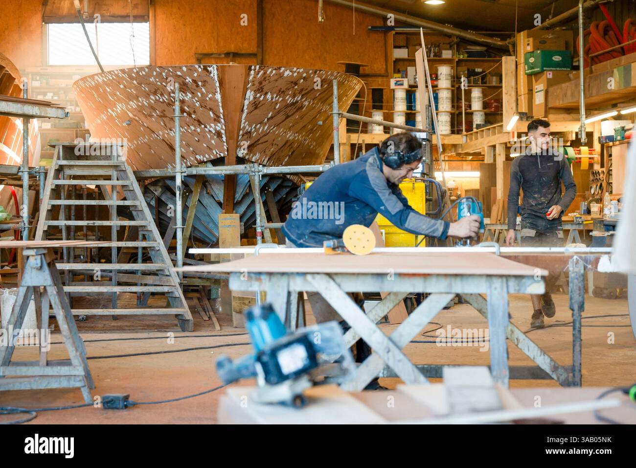 France, Gironde, bassin d'Arcachon, Gujan Mestras, port de Larros, chantier naval de Dubourdieu, le plus ancien chantier naval en exploitation continue en France, fabrication de hors-bord en bois haut de gamme et sur mesure, un menuisier marin découpe des panneaux de coque Banque D'Images