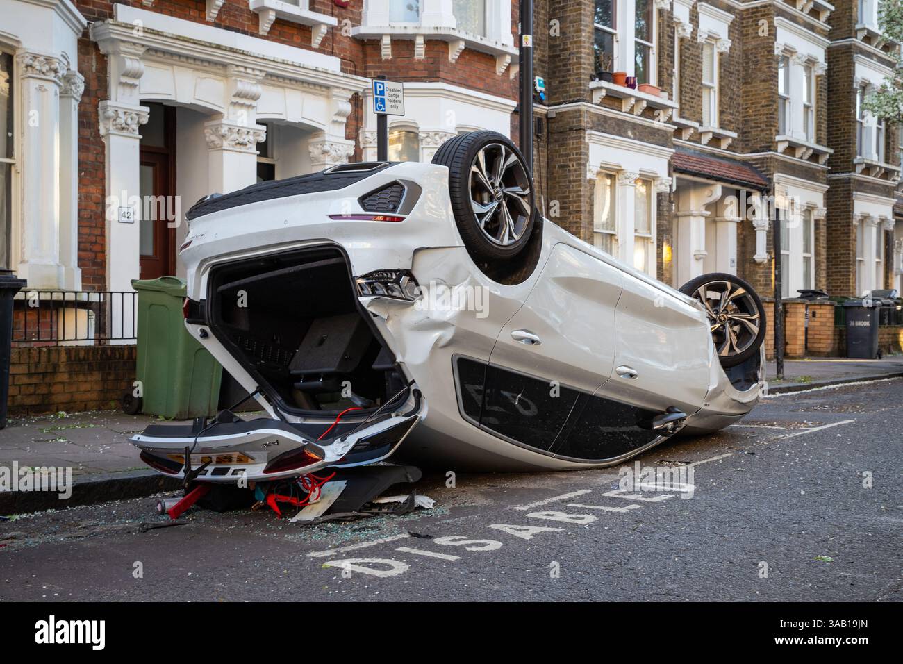 Voiture blanche renversée 'garée' dans une baie pour handicapés dans une rue résidentielle de Londres après un accident de la route Banque D'Images