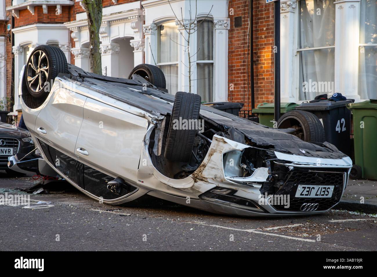 Voiture blanche renversée 'garée' dans une baie pour handicapés dans une rue résidentielle de Londres après un accident de la route Banque D'Images
