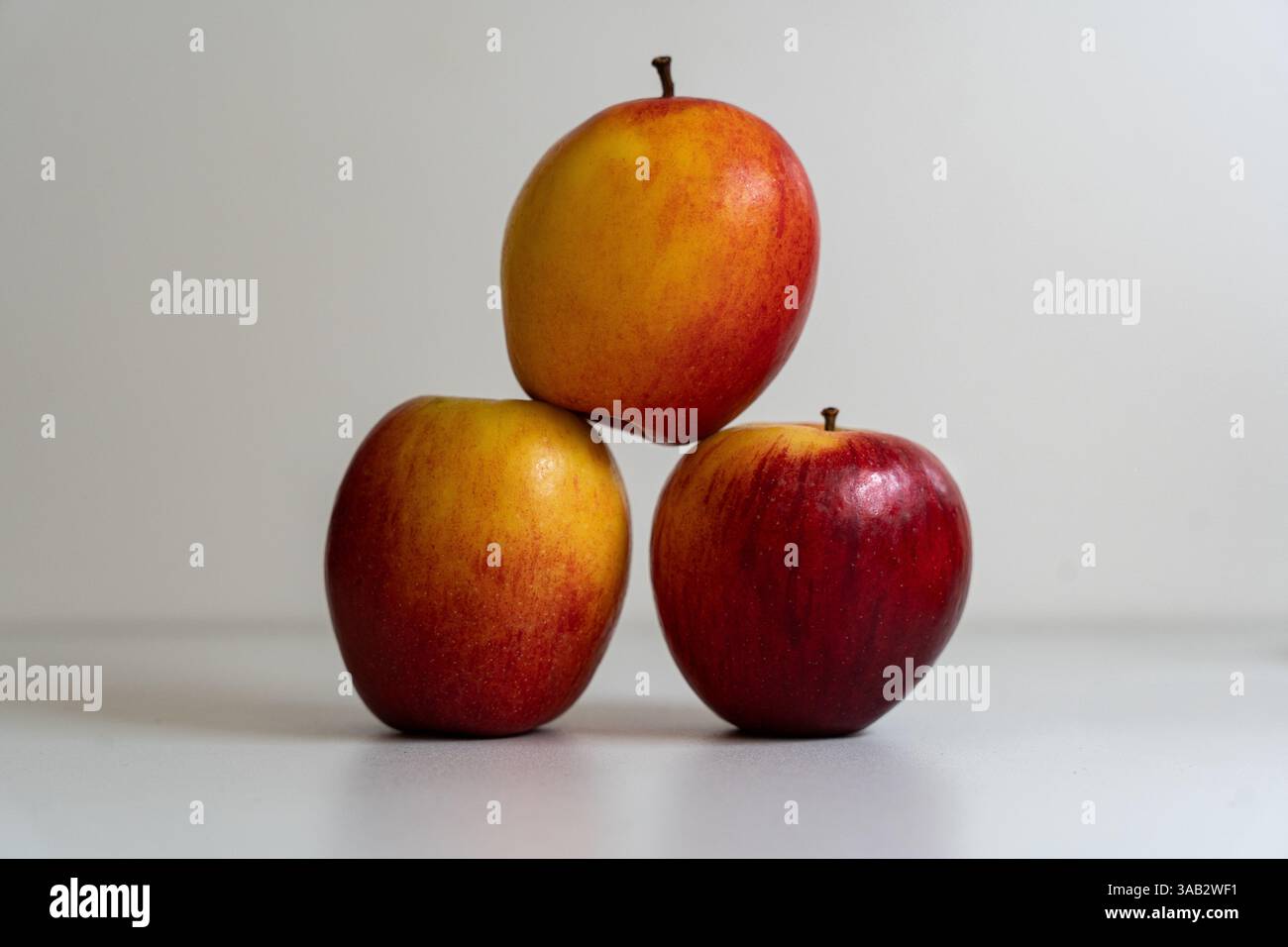 3 pommes empilées pour faire une pyramide sur fond blanc. Banque D'Images