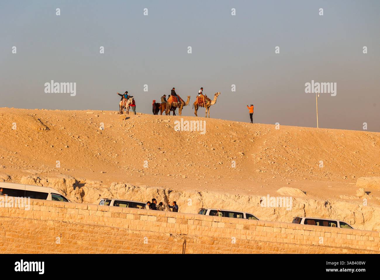 Touristes sur une balade à dos de chameau dans les sables du désert du complexe pyramidal de Gizeh en Egypte Banque D'Images