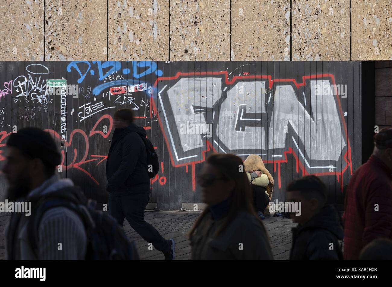 Passants passant devant un sans-abri devant un mur de graffiti dans une zone piétonne, Bavière, Allemagne, Europe Banque D'Images