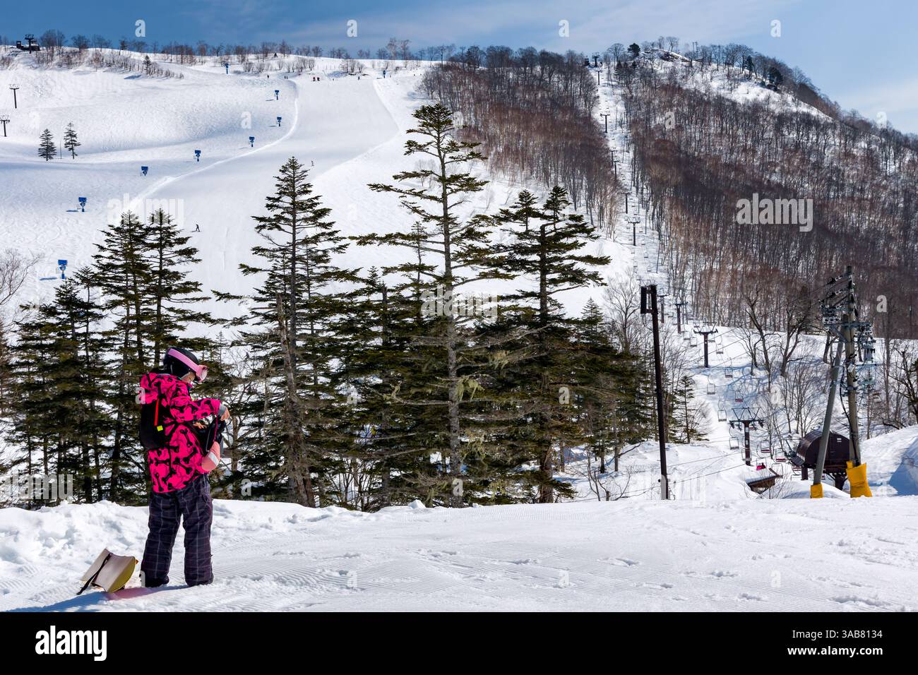 Snowboardeuse célibataire au sommet d'une piste de ski par jour ensoleillé Banque D'Images