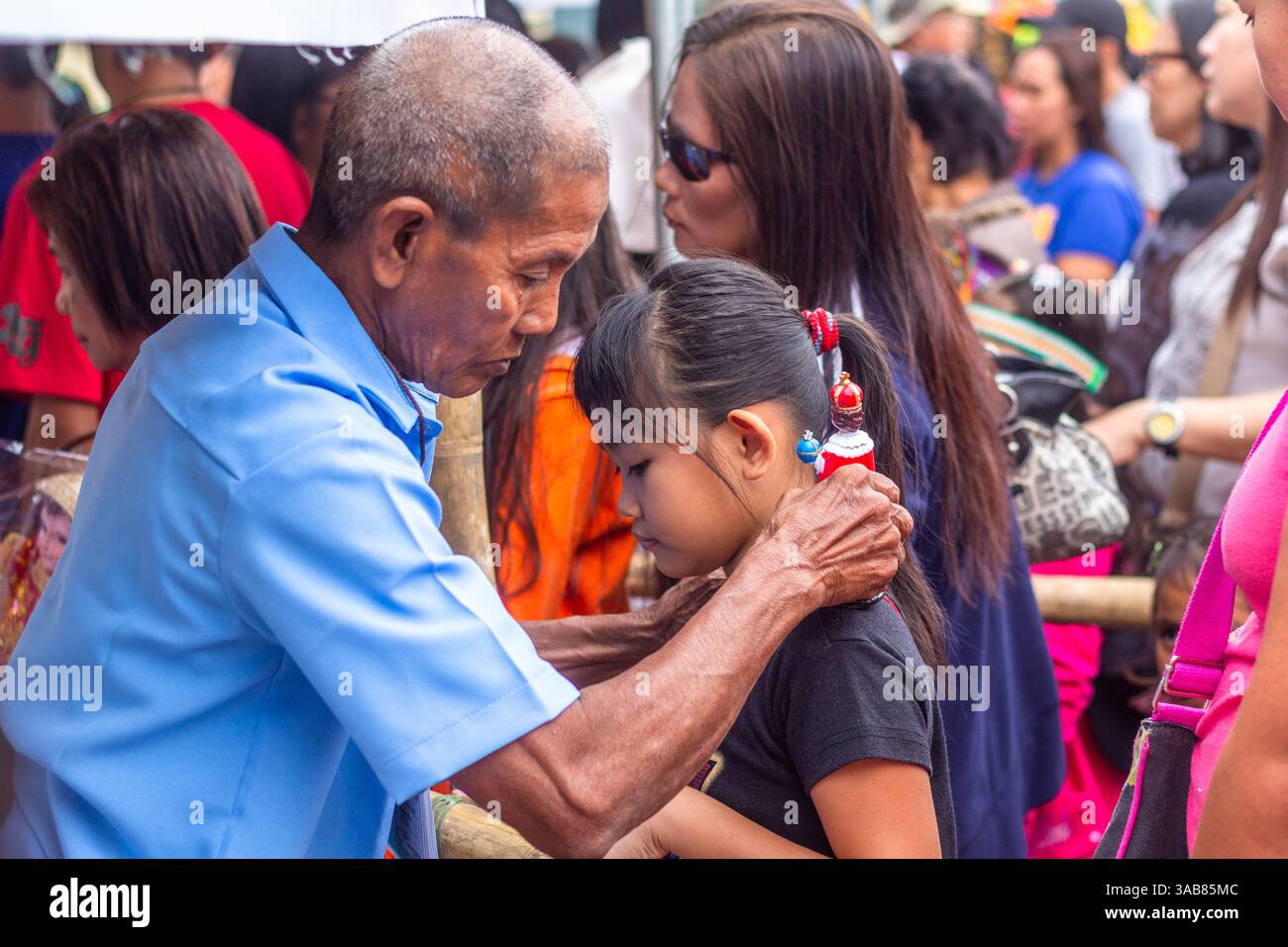 Un vieil homme bénit une fille philippine en touchant une image du Sto. Niño sur son front lors du Festival ATI-Atihan à Kalibo, Philippines Banque D'Images