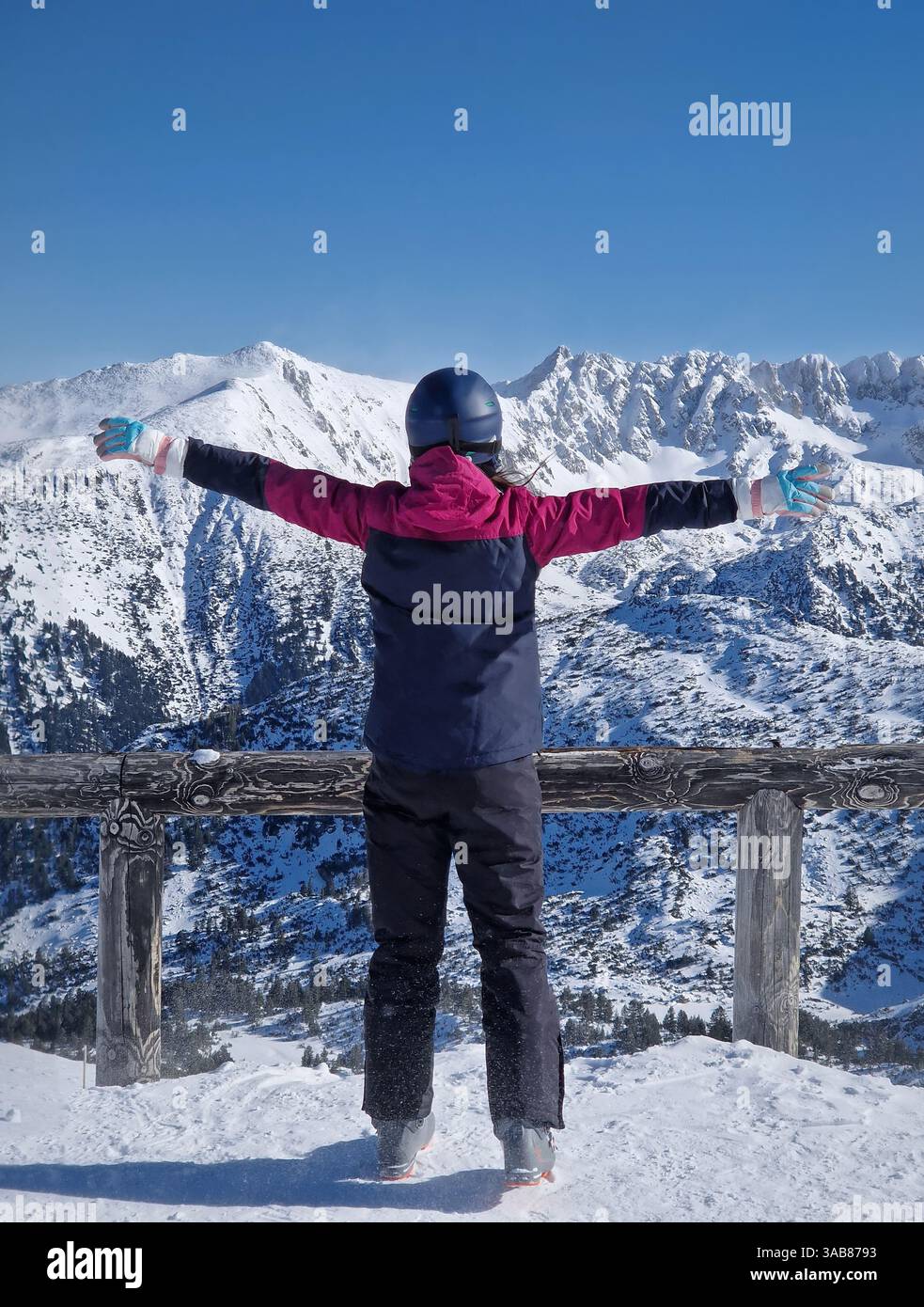 Vue arrière femme skieuse sur le sommet de la montagne debout avec les bras grands ouverts face à la neige couverte pics Pirin à la station de ski de Bansko, Bulgarie. Scène avec un fe - Image de stock capturée avec un smartphone