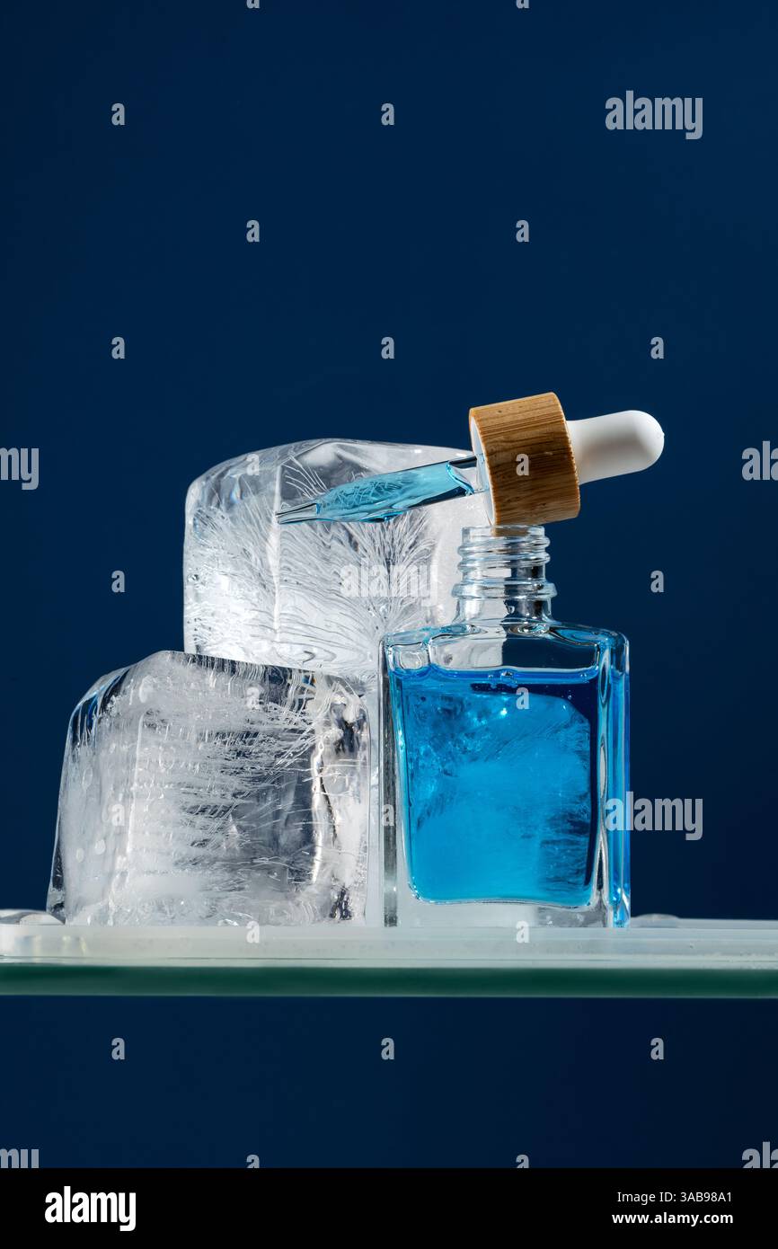 Sérum de soin du visage pour hommes dans un flacon compte-gouttes, conçu pour un effet rafraîchissant. La prise de vue macro capture la pipette au milieu de la glace, mettant en évidence une fraîche et R Banque D'Images