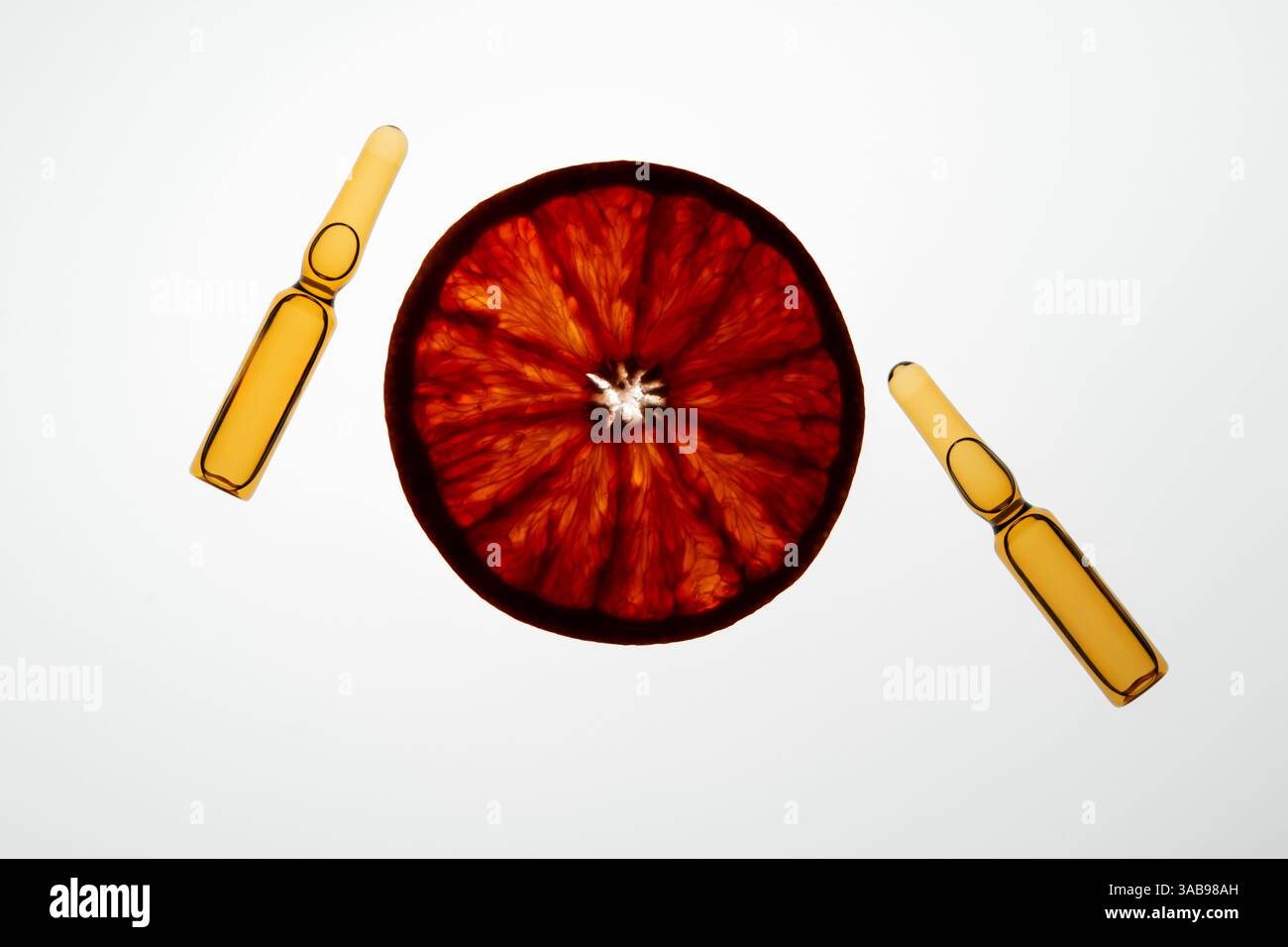 Une orange tranchée et deux ampoules créent un thème de santé et de bien-être vibrant sur un fond blanc. La composition souligne la signification de vita Banque D'Images