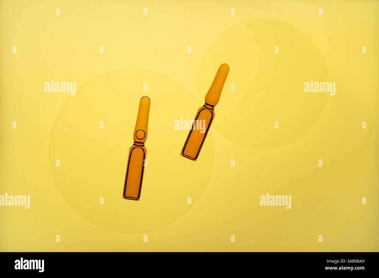 Deux ampoules ambrées sont élégamment disposées sur un fond jaune vif, créant une composition minimaliste et artistique. La conception met en évidence simpli Banque D'Images