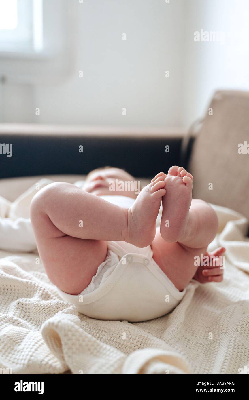 Une image sereine d'une petite fille nouveau-née couchée sur une couverture douce et tricotée. Ses petits pieds sont ludiques, capturant l'innocence et la chaleur de l'infa Banque D'Images
