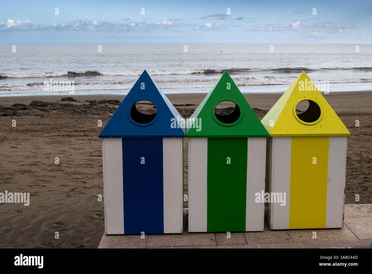 Poubelles bleues, vertes et jaunes pour la séparation des déchets sur la plage de l'océan Atlantique. Ciel avec des nuages légers. Castillo del Romeral, Las Palma Banque D'Images