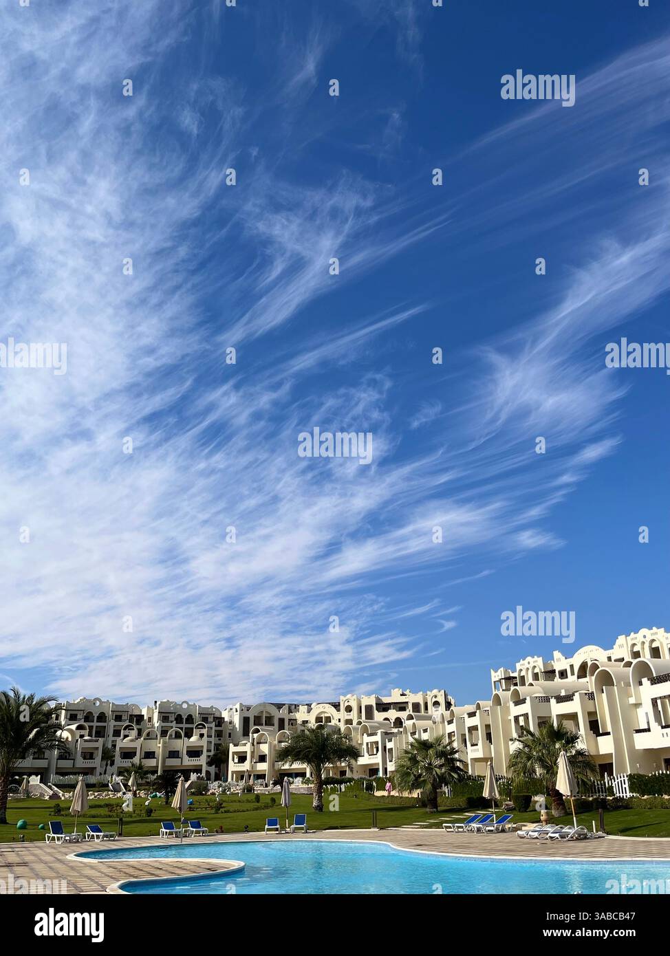 Nuages uniques inhabituels sur une journée ensoleillée avec le ciel bleu le novembre dans l'hôtel égyptien, destination de vacances, palmiers et herbe verte, vue spectaculaire - Image de stock capturée avec un smartphone