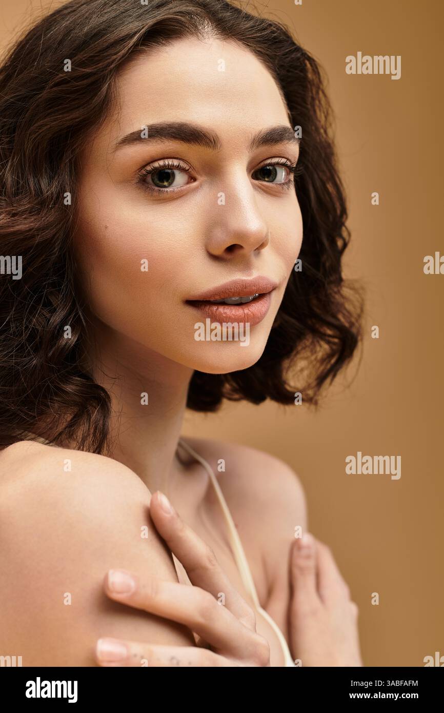 Une jolie jeune femme avec des bretelles démontre sa routine beauté dans une ambiance de studio sereine. Banque D'Images