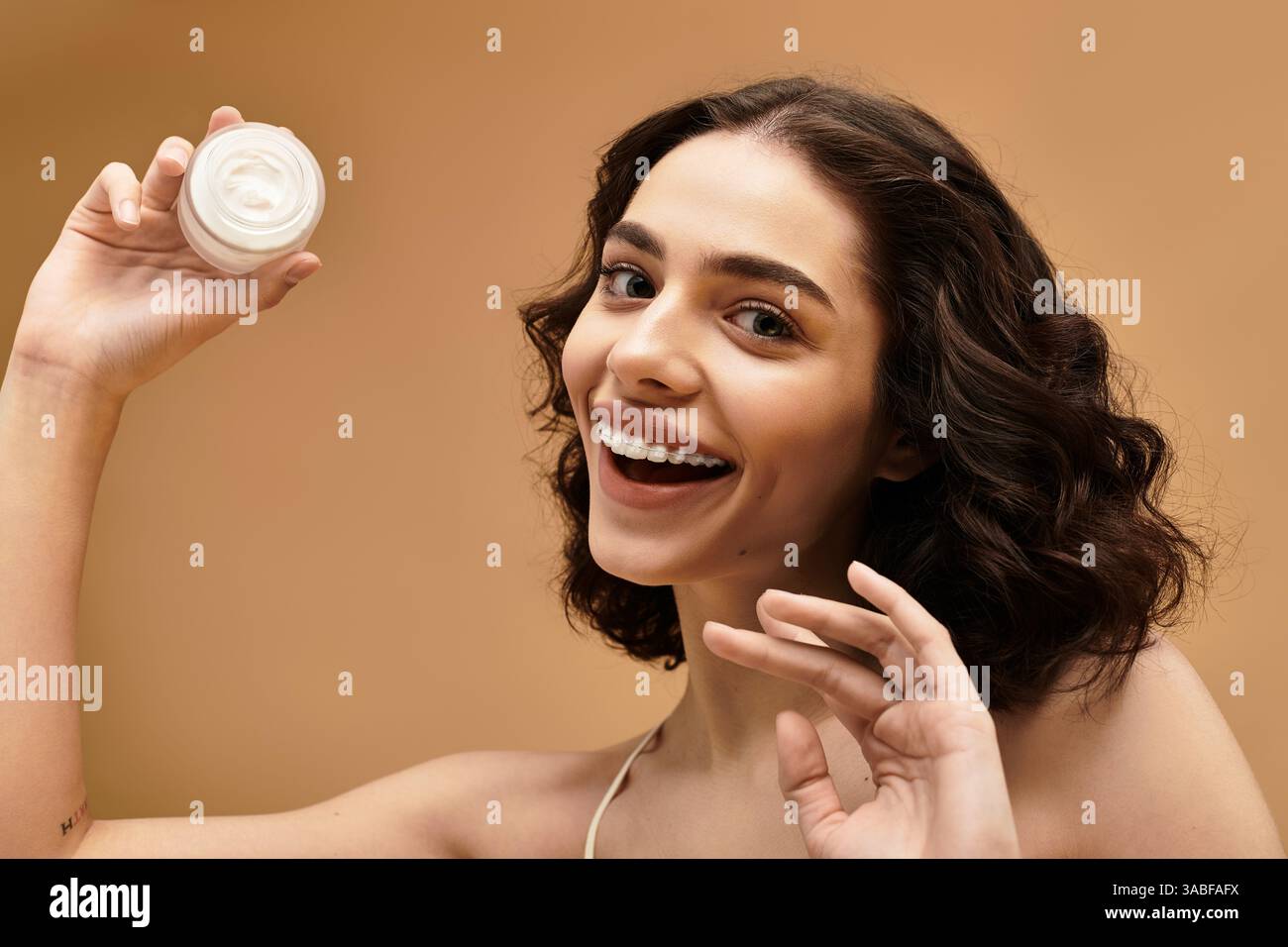 Jeune femme brillante et joyeuse démontre sa routine beauté tout en mettant en valeur la peau rayonnante. Banque D'Images