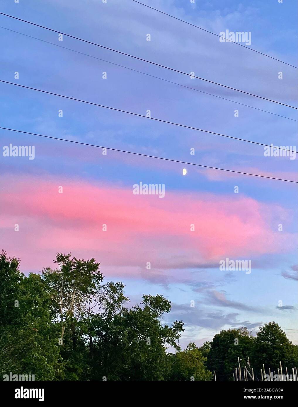 Un ciel de coucher de soleil fascinant peint dans des teintes roses, bleues et violettes douces, ressemblant à une barbe à papa, tandis que la lune est visible dans le ciel du soir. - Image de stock capturée avec un smartphone