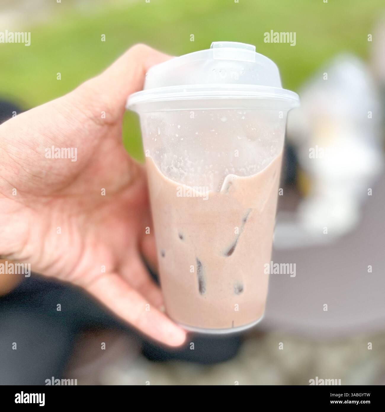 Main masculine tenant tasse de lait au chocolat doux avec fond flou - Image de stock capturée avec un smartphone