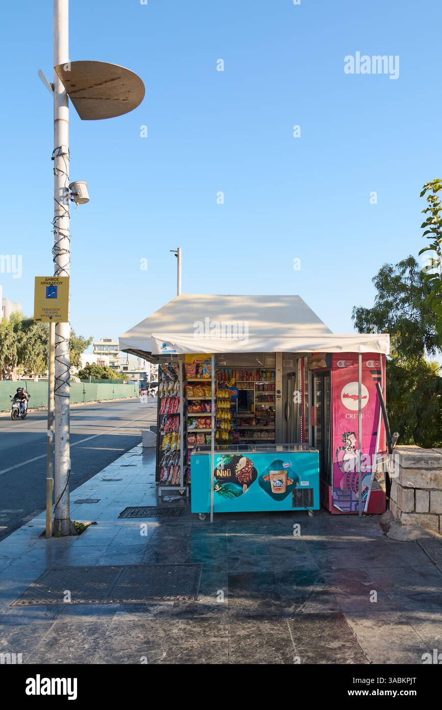 Crète. Grèce - 02 avril 2025 : kiosque de rue dynamique vendant des collations, des boissons et des glaces, avec une canopée ombragée et un cadre urbain animé avec p Banque D'Images