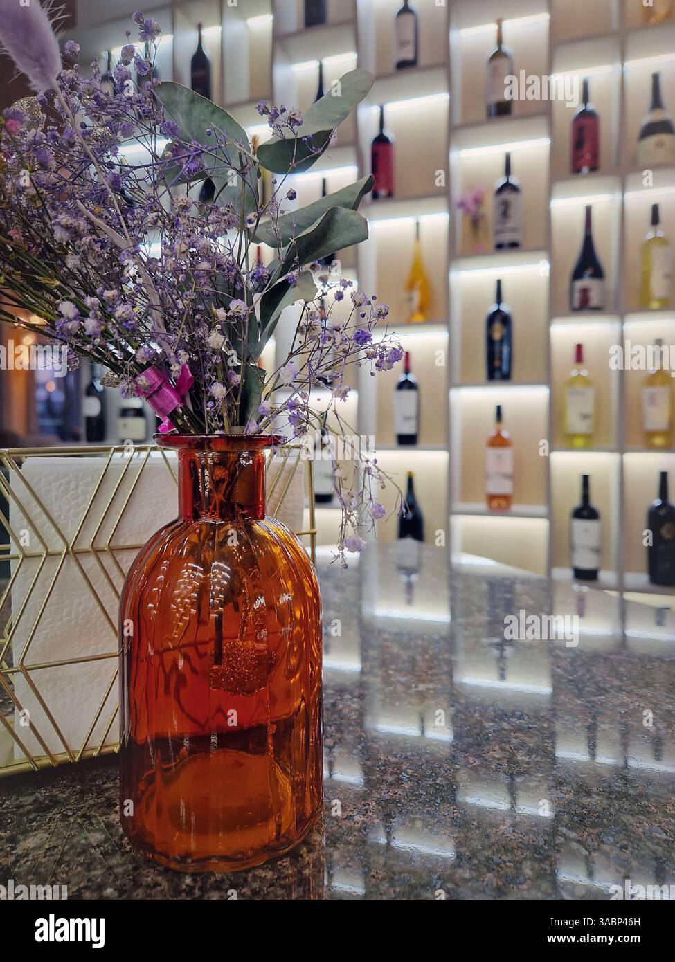 Vue intérieure du restaurant de fantaisie avec vase fleuri sur la table et une vue sur les étagères de vin sur le fond - Image de stock capturée avec un smartphone