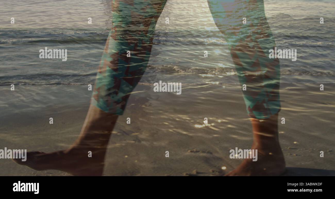 Image des jambes de l'homme marchant sur la plage, au-dessus du soleil sur la mer Banque D'Images