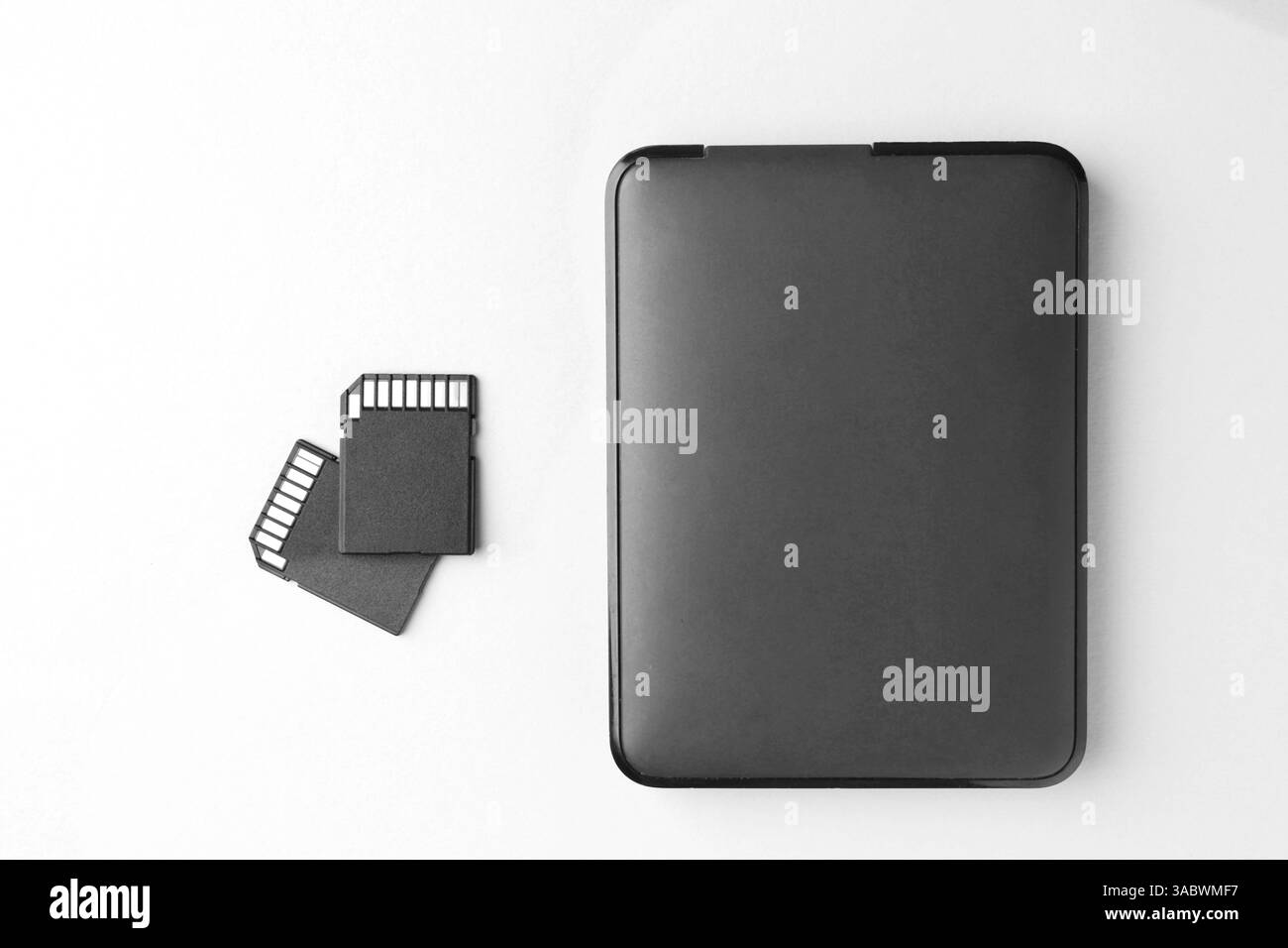 Disque dur externe et cartes mémoire SD sur fond blanc, plat Banque D'Images