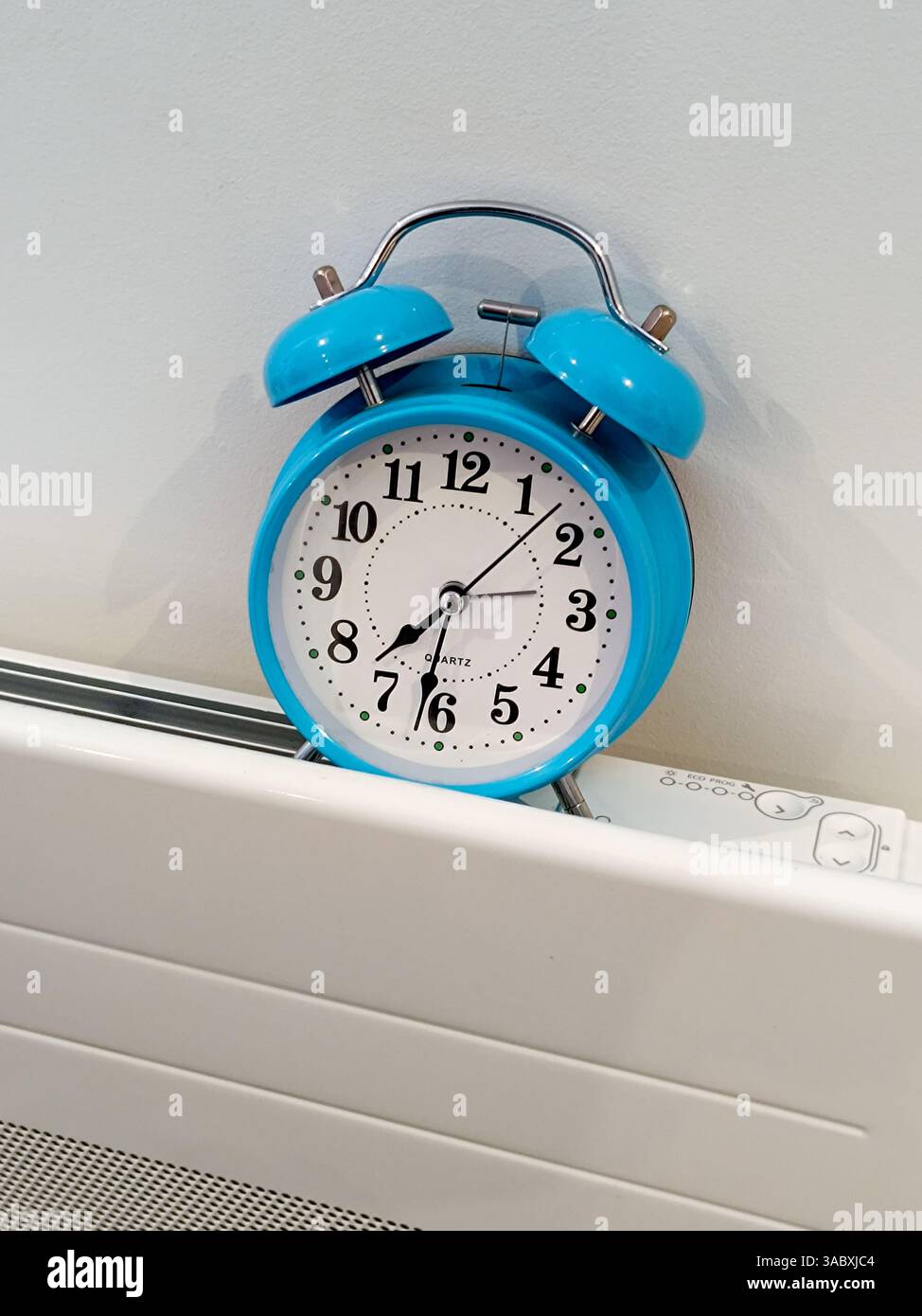 Réveil bleu posé sur un radiateur affichant 19 degrés. Banque D'Images