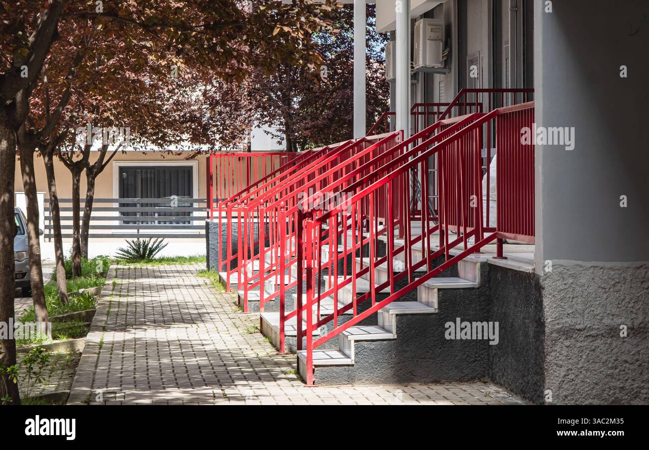 Marches en béton et garde-corps en fer dans une rangée. Vue sur la rue des mains courantes en acier peintes en couleur rouge aux escaliers d'un immeuble résidentiel, en acier Banque D'Images