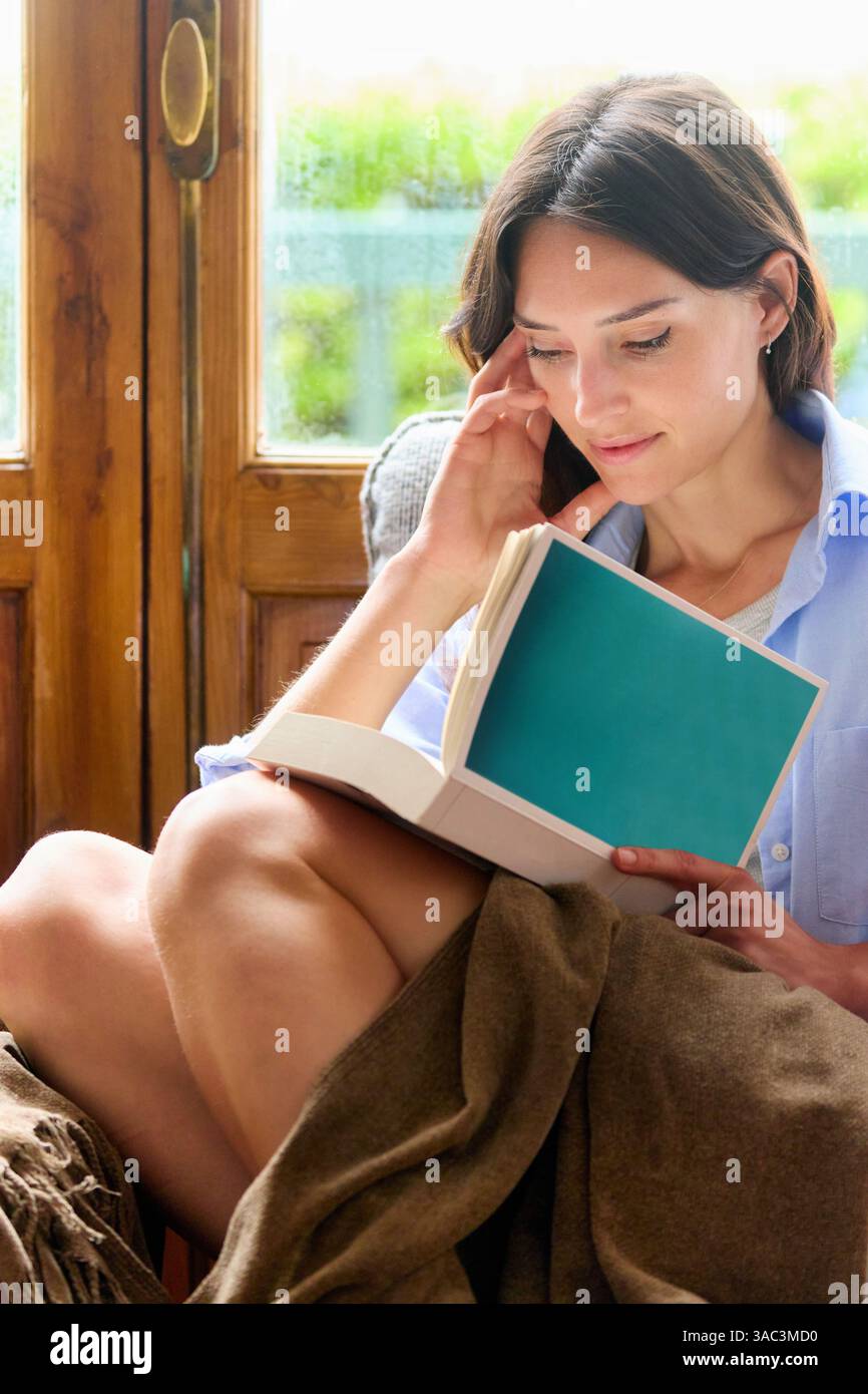 femme de 35 ans à la maison, lisant un livre Banque D'Images