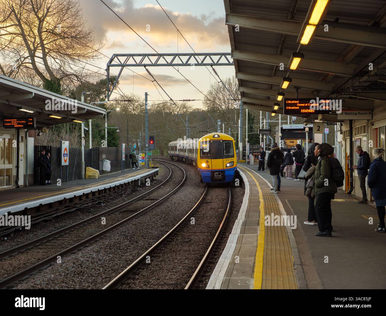 Train London Overground tirant dans la gare alors que les gens attendent sur le quai pour embarquer, Londres, Royaume-Uni Banque D'Images