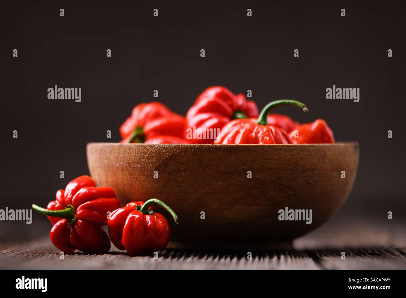 Bol en bois rempli de poivrons rouges habanero mûrs (capsicum chinense) sur table rustique. Les poivrons mexicains très chauds se rapprochent Banque D'Images