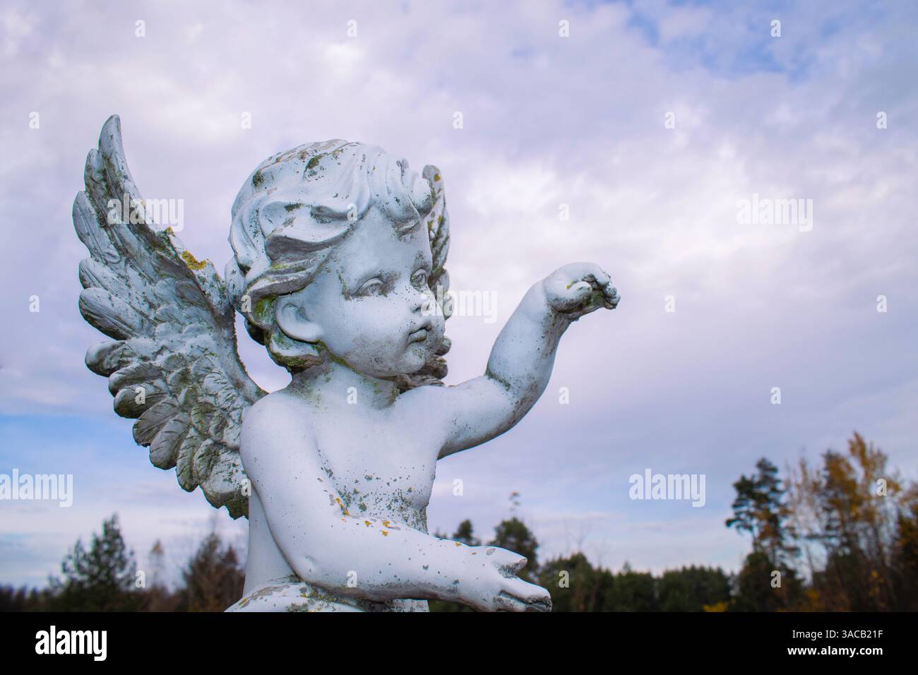 Sculpture en marbre ange gardien blanc avec de longues ailes ouvertes à travers le cadre contre un ciel bleu ensoleillé lumineux avec des nuages blancs clairs. Sculpture mains holdi Banque D'Images