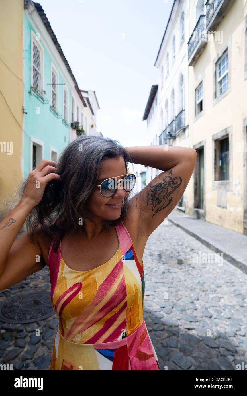 Portrait de belle femme portant une robe colorée et des lunettes de soleil avec les mains dans les cheveux. Personne voyageant. Amérique du Sud. Banque D'Images