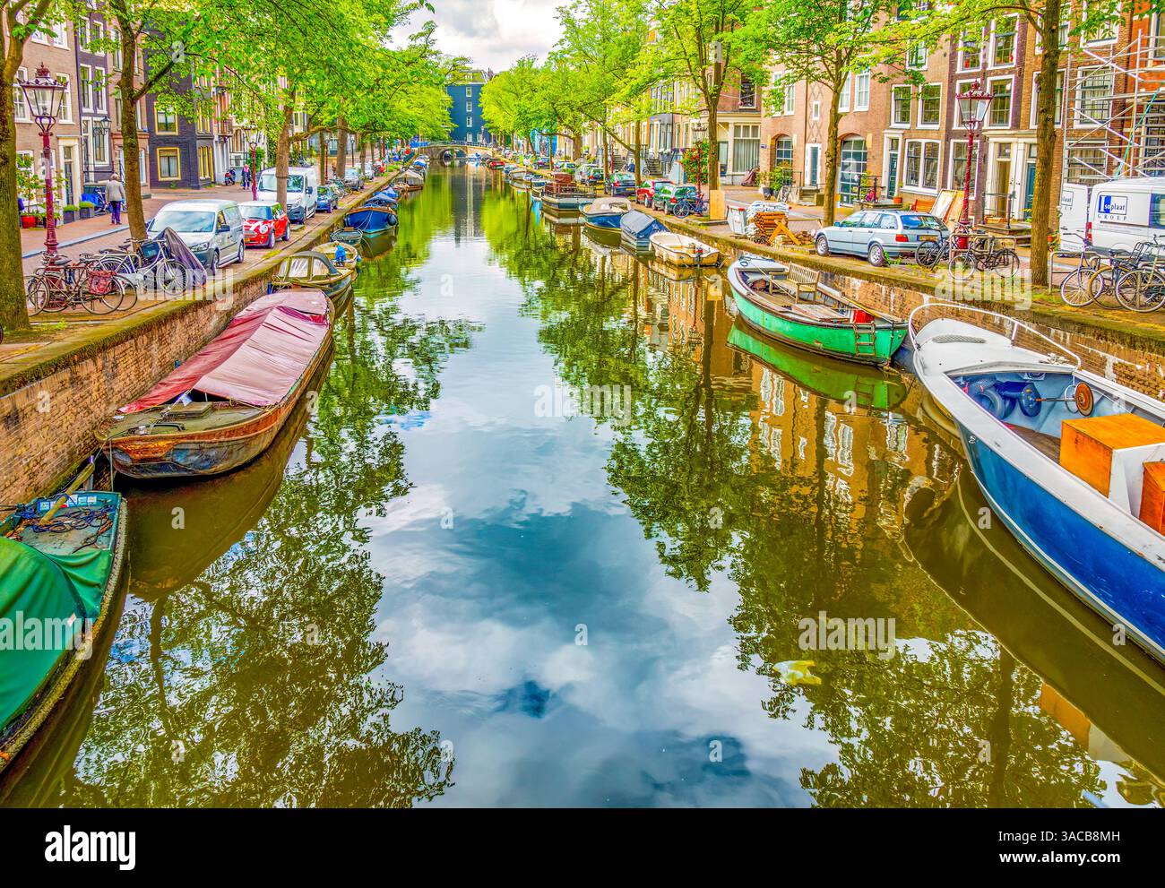 Amsterdam, pays-Bas. Vue panoramique sur les péniches, les bateaux à moteur et les voiliers bordant un canal un jour d'été. Banque D'Images