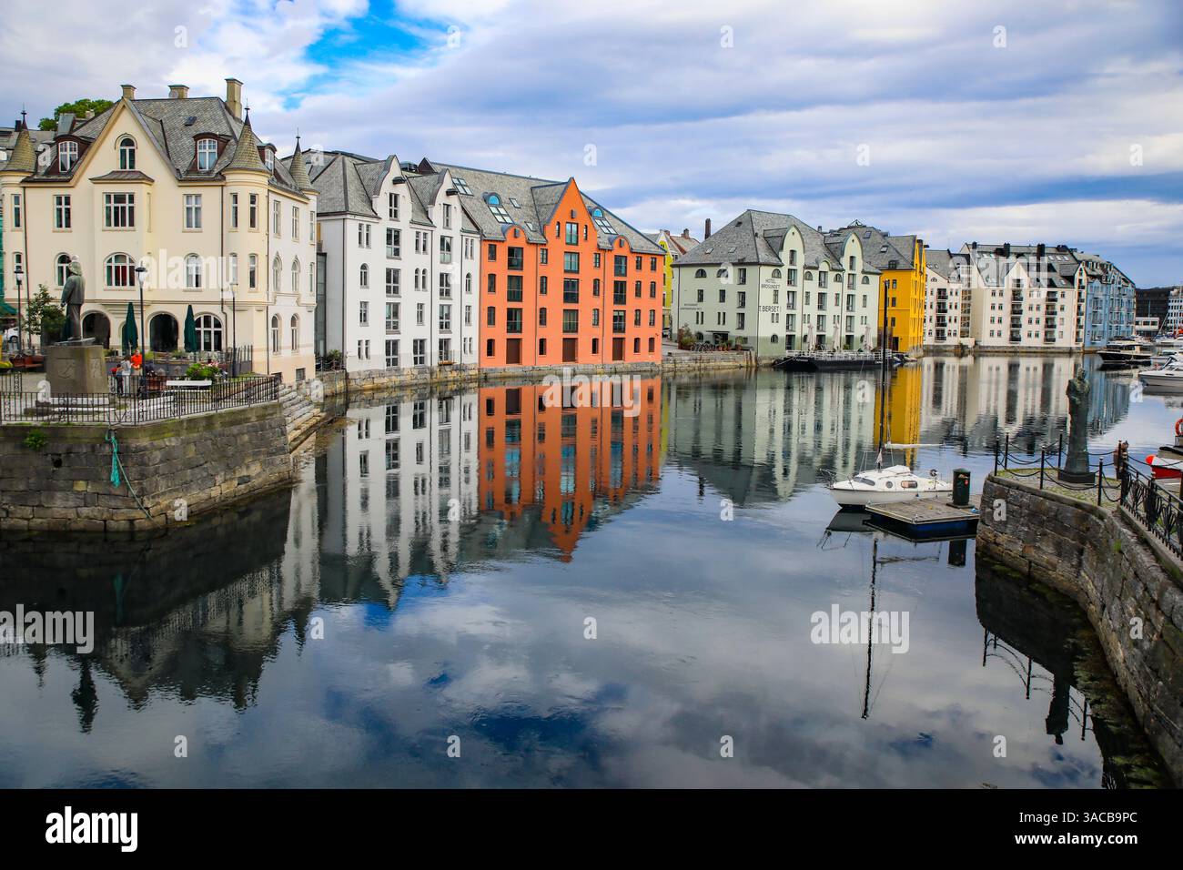 Alesund, Norvège. Canal avec des maisons colorées peintes, bateaux, port de plaisance, statue de marin. Banque D'Images