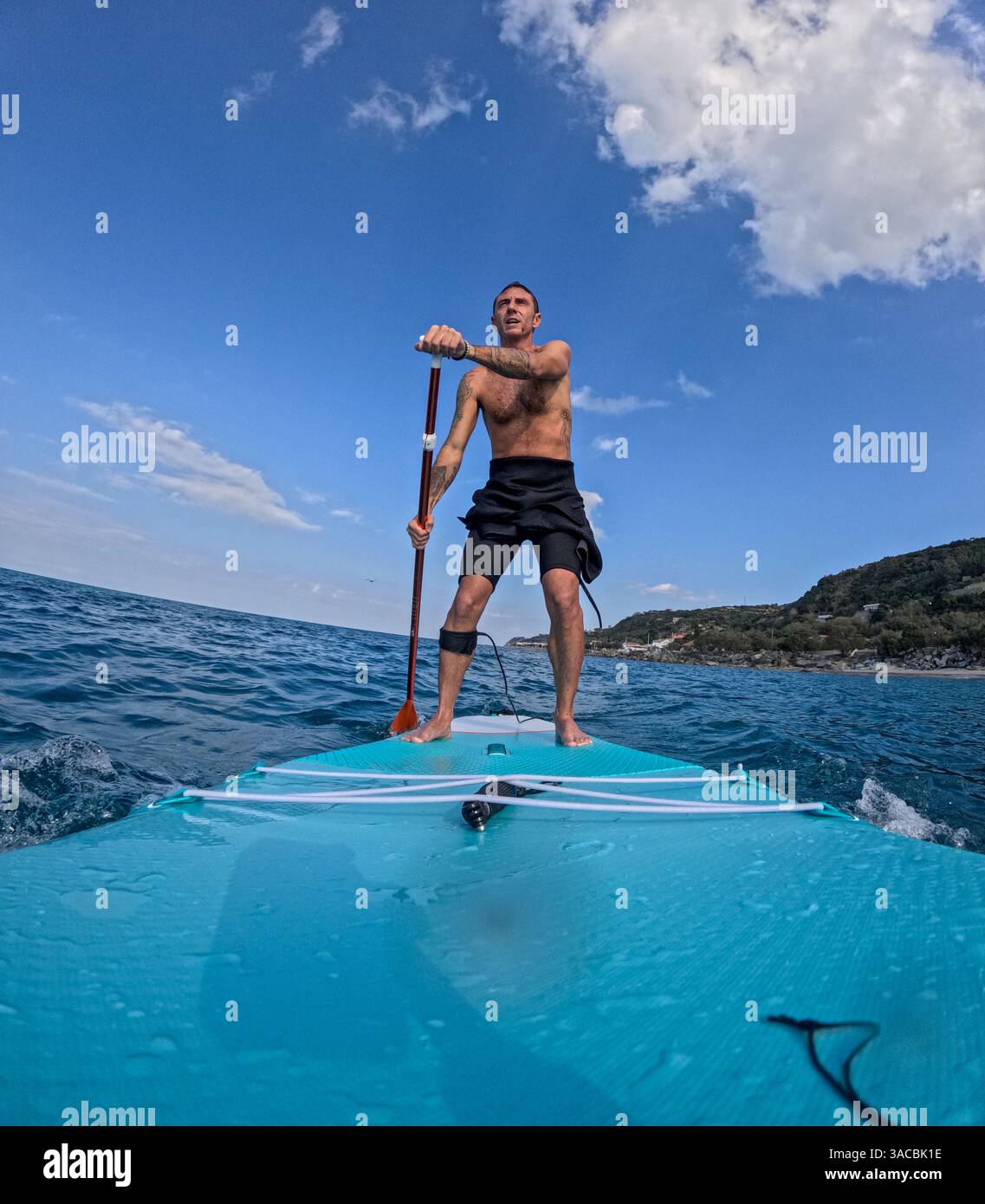Homme italien faisant du stand up paddle surf dans la Méditerranée au large de la côte sicilienne Banque D'Images