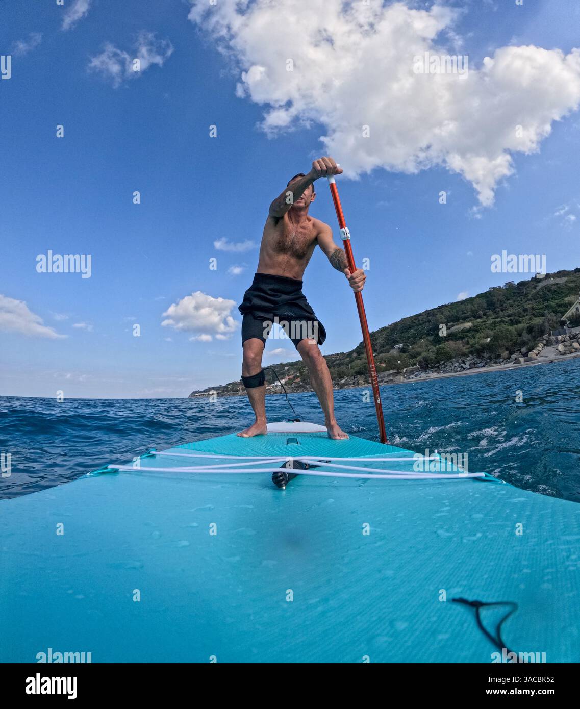 Homme italien faisant du stand up paddle surf dans la Méditerranée au large de la côte sicilienne Banque D'Images