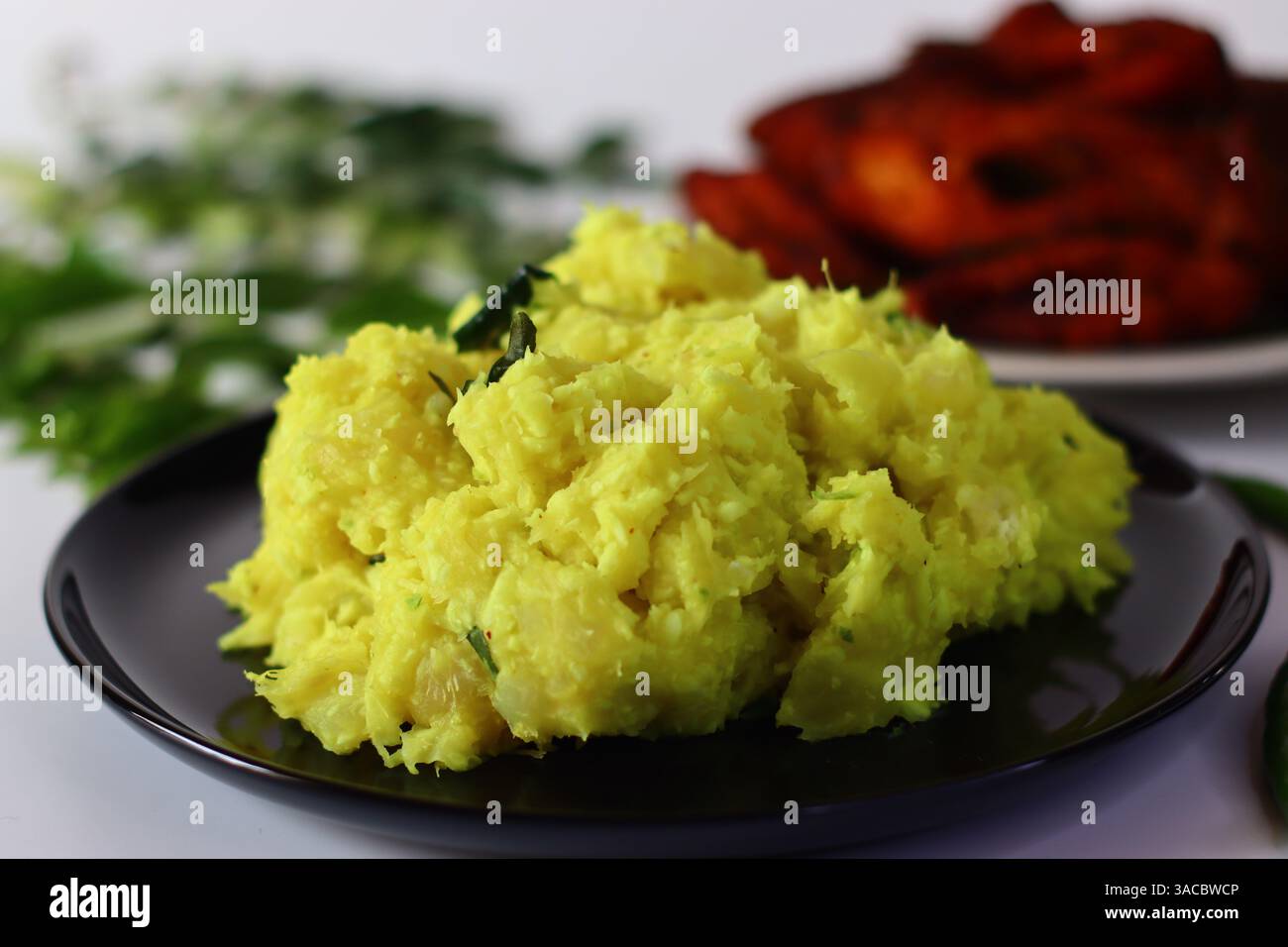 Tapioca bouilli et écrasé mélangé avec du curcuma, des piments verts et des feuilles de curry, servi avec du poisson frit croustillant. Capturé à un angle de surbrillance Banque D'Images