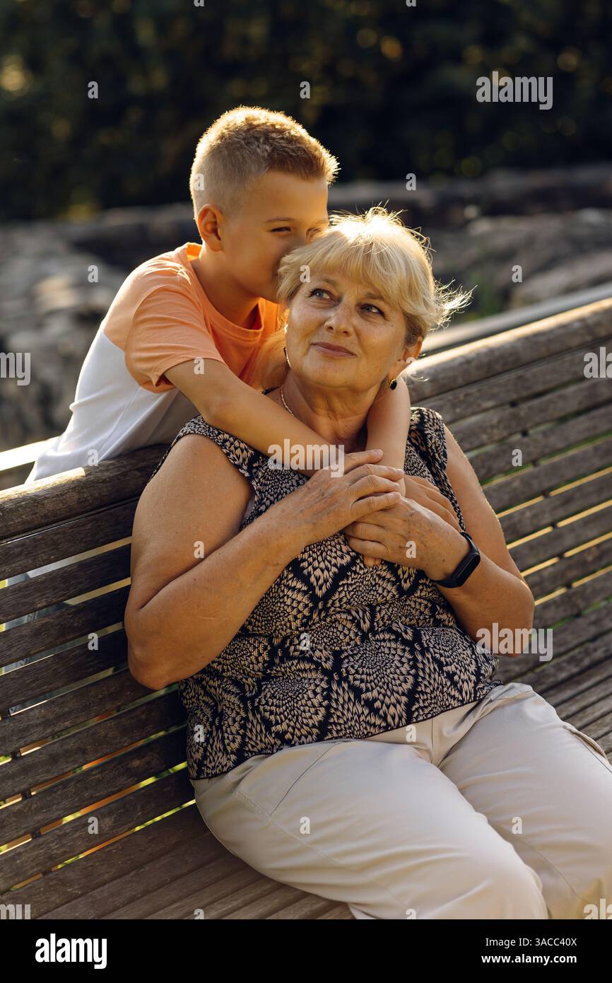 Heureuse grand-mère avec petit-fils ensemble en fauteuil roulant à l'extérieur. Banque D'Images