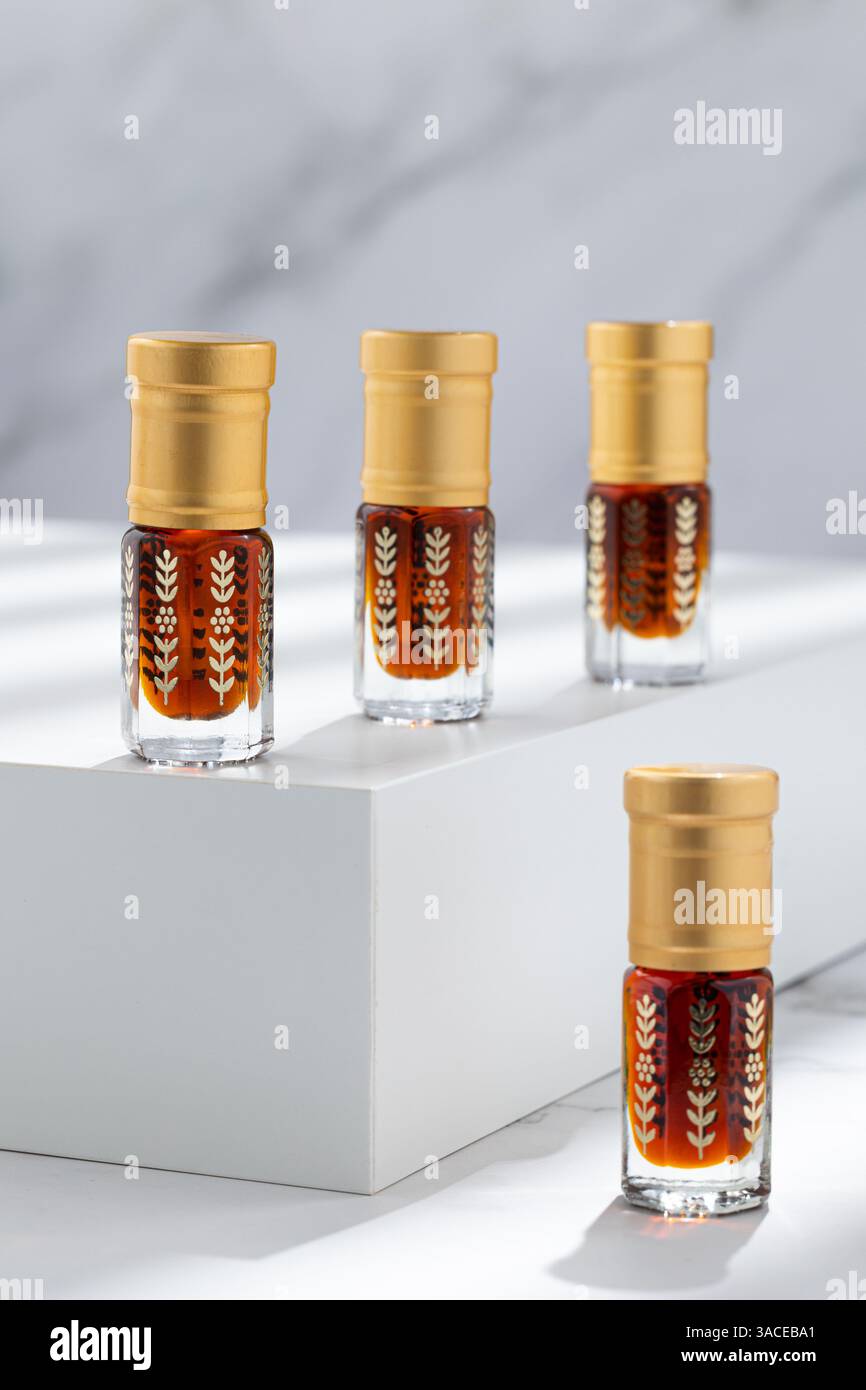 Bouteilles d'huile traditionnelles Oud - Dhn Al Oud sur marbre blanc avec lumière dure et lignes d'ombre Banque D'Images