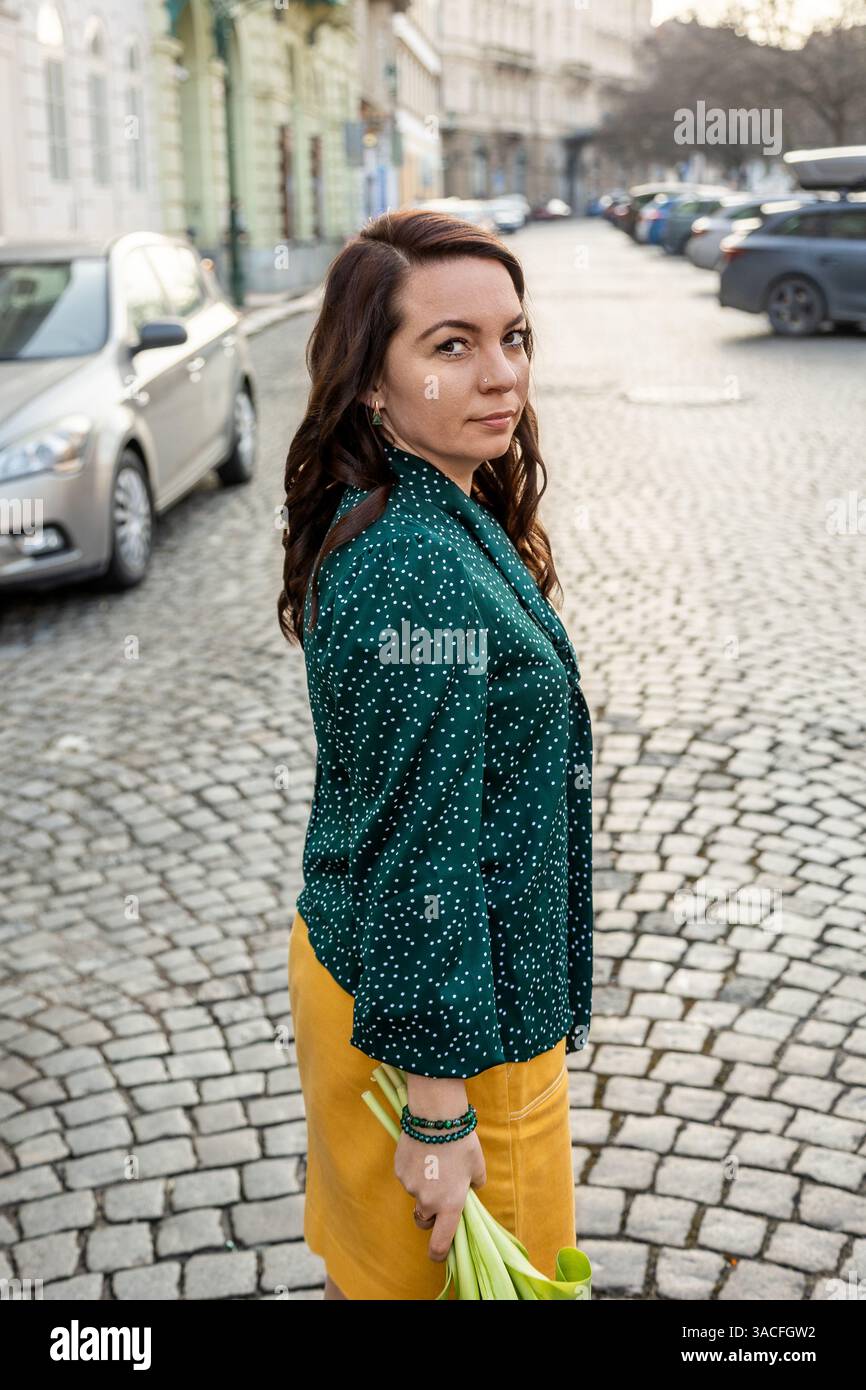 Femme sérieuse debout sur une rue pavée dans la ville Banque D'Images