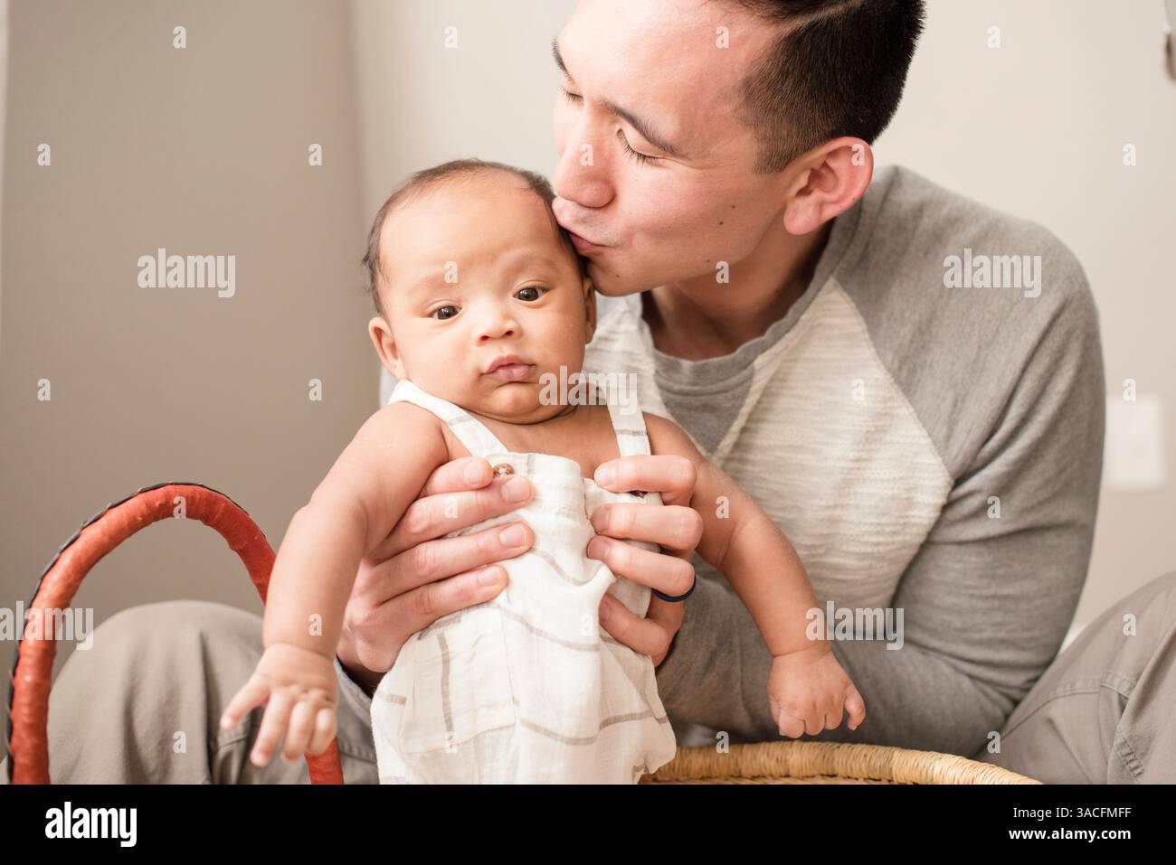Père embrasse bébé sur la tempe tout en les tenant doucement debout Banque D'Images