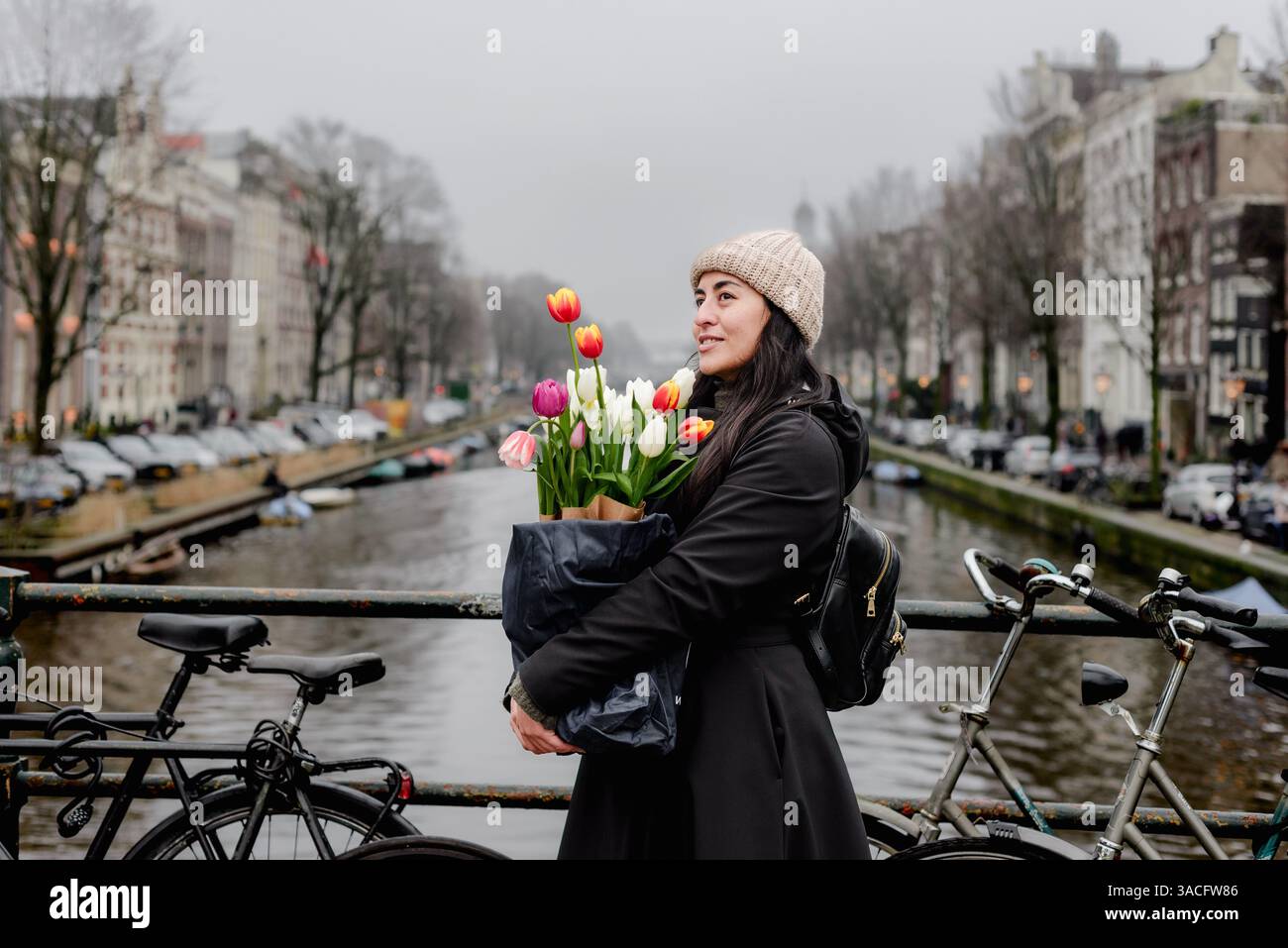Femme tenant des tulipes colorées sur le pont sur le canal d'Amsterdam Banque D'Images
