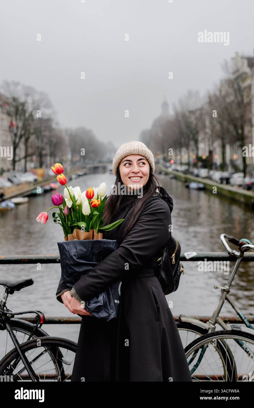 Femme tenant des tulipes dans Amsterdam canal Bridge scène Banque D'Images
