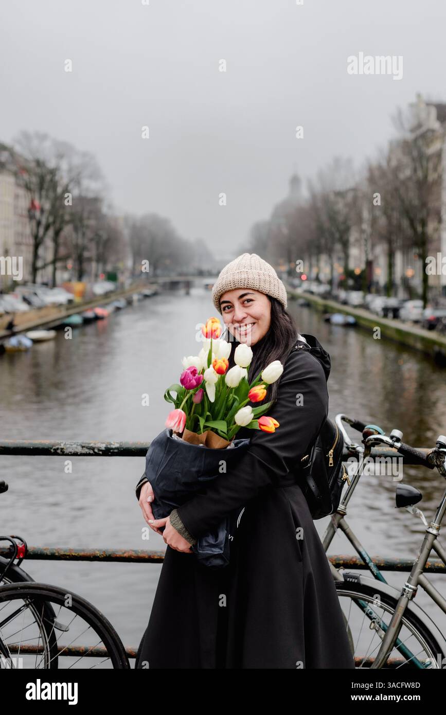 Femme souriante avec bouquet coloré de tulipes sur le pont d'Amsterdam Banque D'Images