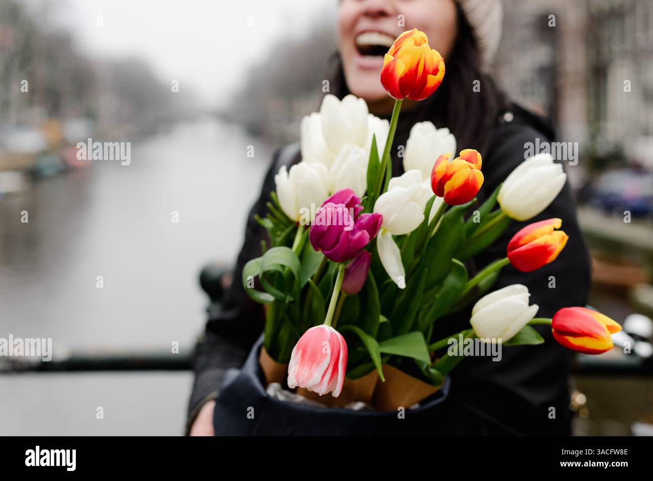 Femme riant tout en tenant lumineux bouquet de tulipes sur le canal d'Amsterdam Banque D'Images