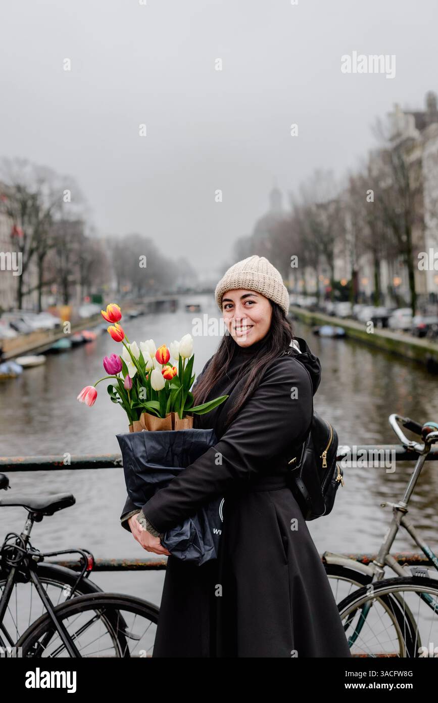 Femme souriant avec des tulipes sur Amsterdam canal Bridge en hiver Banque D'Images