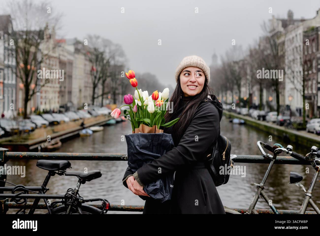Femme tenant des tulipes sur Amsterdam canal Bridge entouré de vélos Banque D'Images