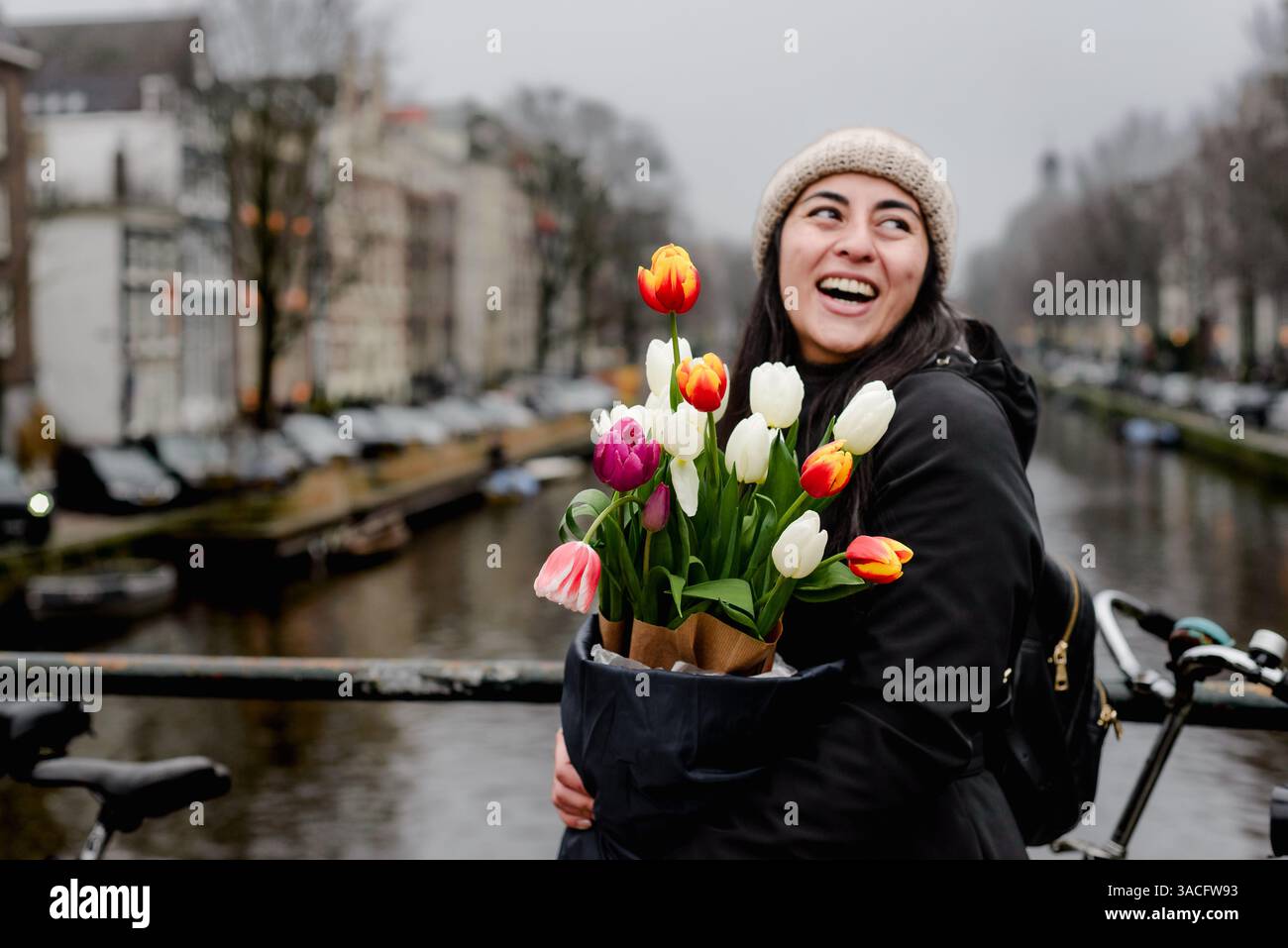 Femme joyeuse avec bouquet de tulipes coloré sur Amsterdam canal Bridge Banque D'Images