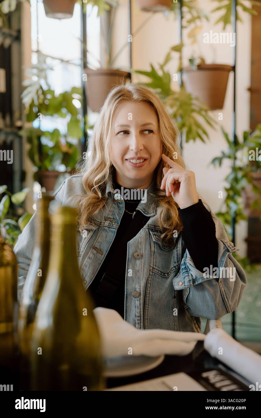 Femme en veste denim souriant à la table du restaurant Banque D'Images